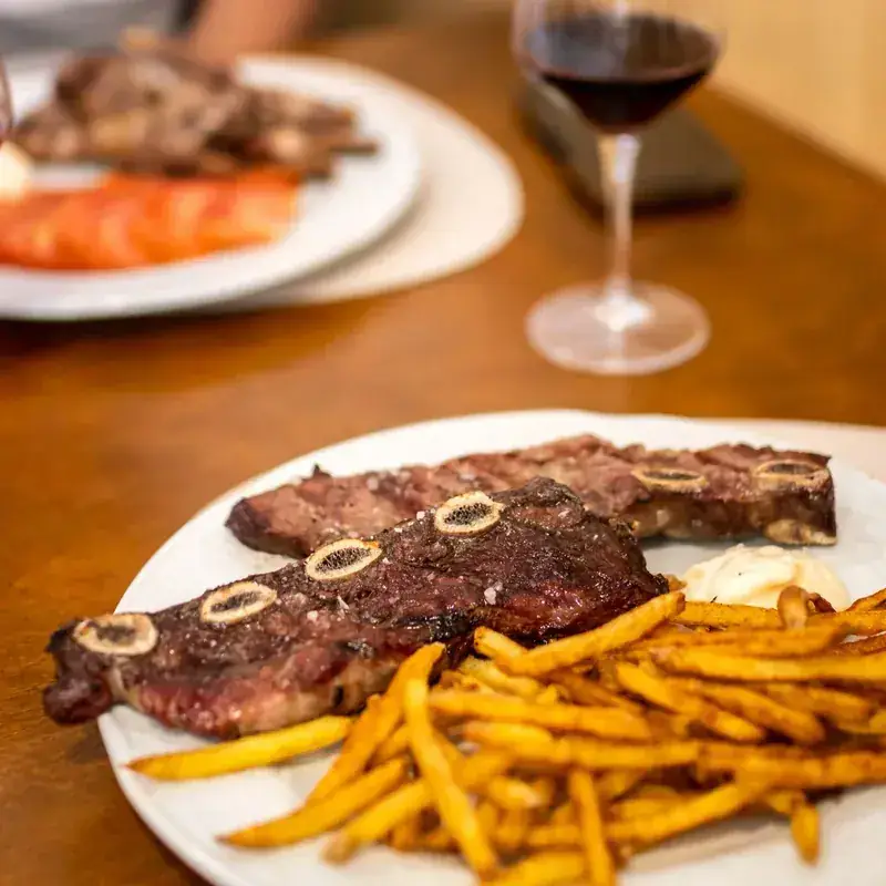 Churrasco a la brasa con patatas y una copa de vino