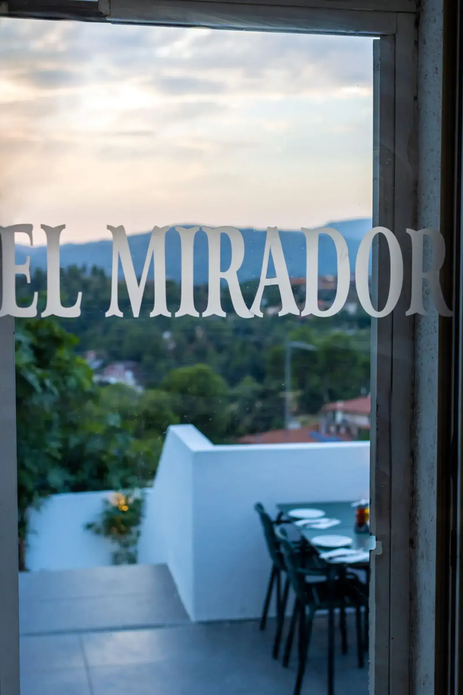 El rótulo de El Mirador Gallego en el cristal, con la terraza y el valle al fondo